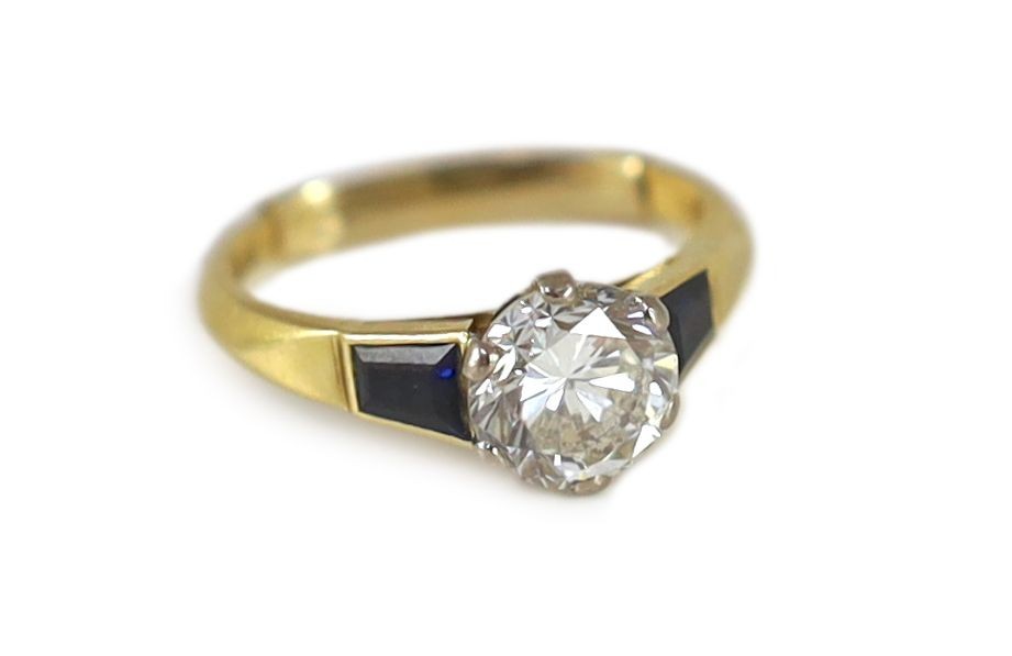A modern 18ct gold and single stone diamond ring, with trapeze cut sapphire set shoulders